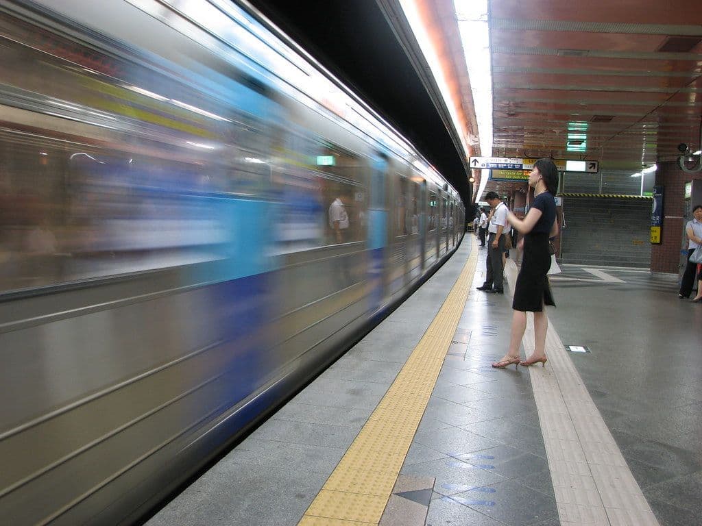 Passengers waiting on a Seoul subway platform as a train arrives